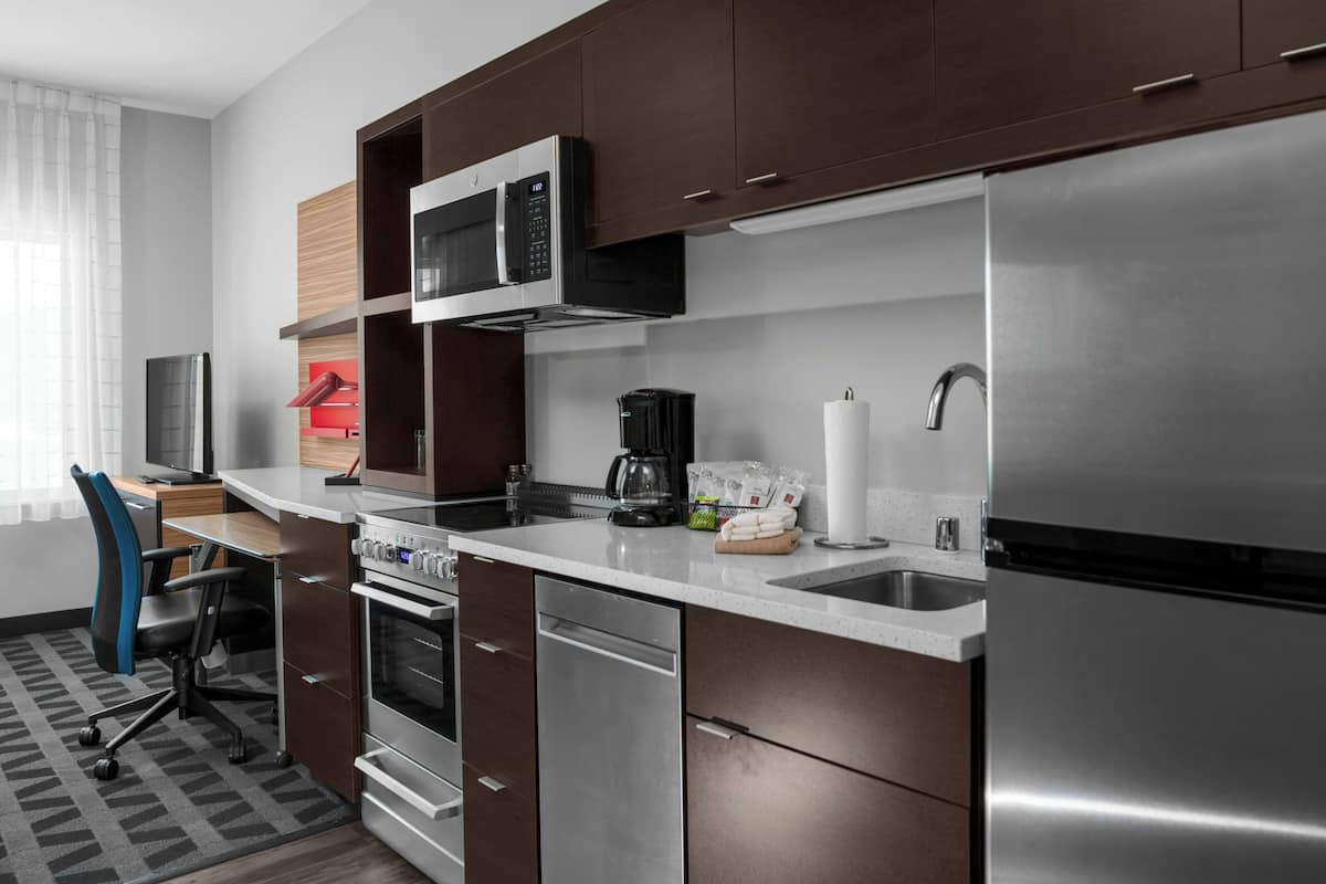Una cocina moderna con electrodomésticos de acero inoxidable, microondas integrado y cafetera.