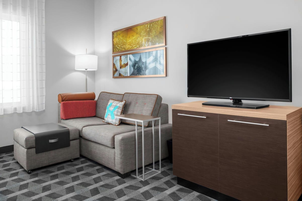 Una sala de estar moderna con un sofá seccional, un televisor de pantalla plana, una mesa de centro y un mueble.