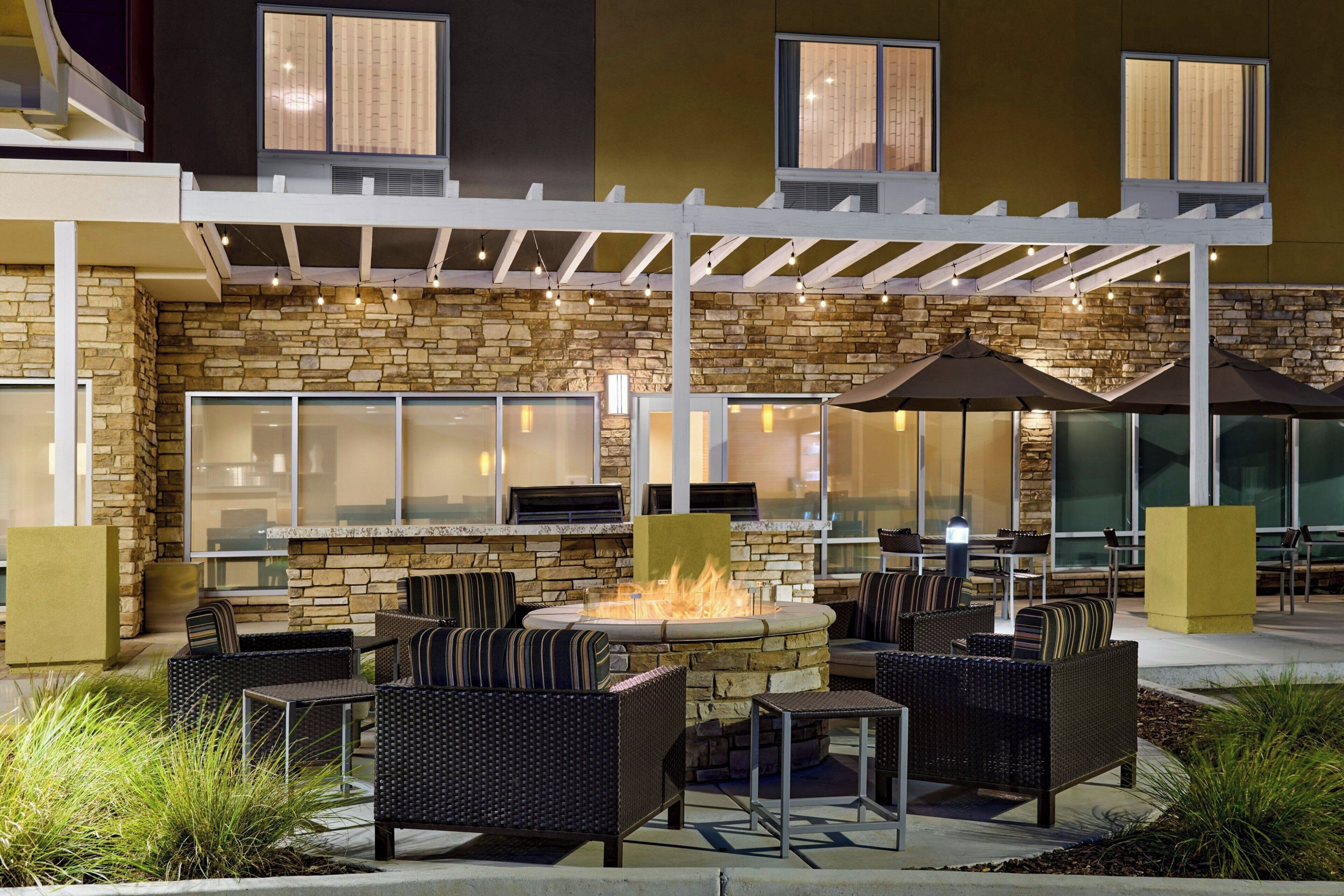 An outdoor patio with stone walls, wicker furniture, and a fire feature.