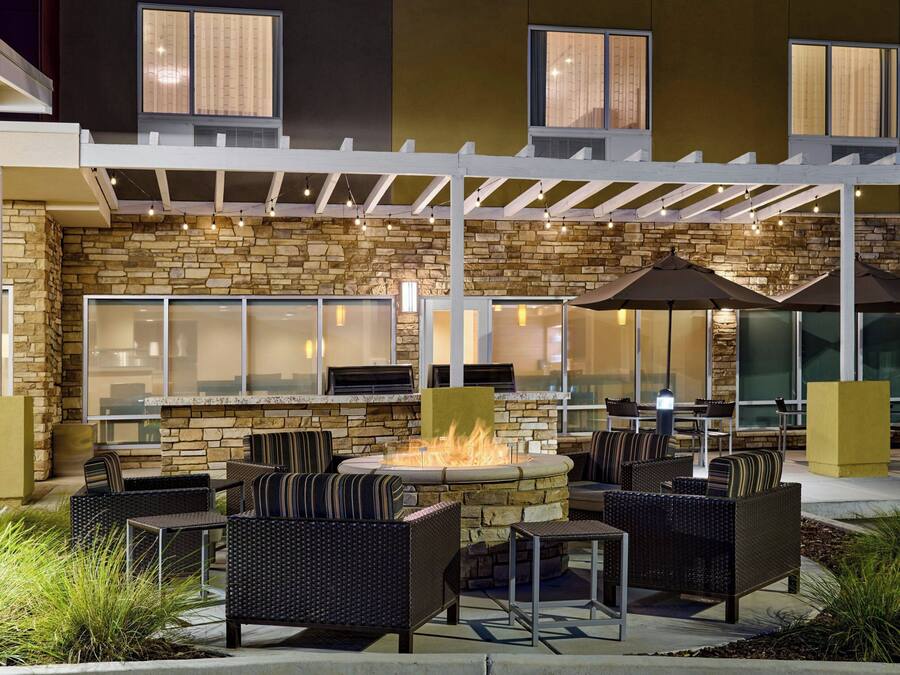 An outdoor patio with stone walls, wicker furniture, and a fire feature.