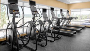 Une salle de sport équipée de tapis de course, d’elliptiques et de vélos d’appartement, dotée de grandes fenêtres et offrant une vue sur l’extérieur.