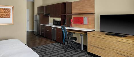 Une chambre d’hôtel équipée d’une kitchenette, d’un téléviseur à écran plat, d’un bureau et d’une chaise.