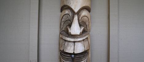 En utskuren trästaty, formad som en totem, som är upphängd på en vägg.