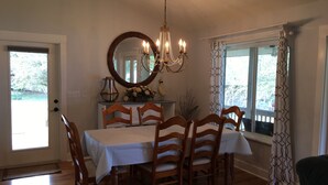 A dining room with a large table, wooden chairs, a chandelier, and a mirror on the wall. - Riverside Retreat (Dunnellon)