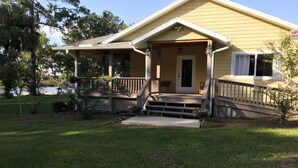 A yellow house with a porch, steps, and a small garden. - Riverside Retreat (Dunnellon)