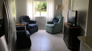 A living room with two armchairs, a television, and a cabinet. - Riverside Retreat (Dunnellon)