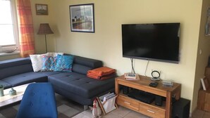 Een woonkamer met een bank, een televisie en een houten tv-meubel.