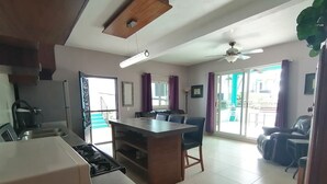 A modern kitchen with a built-in stove, a dining area with a table and chairs, and a sliding glass door leading to a balcony. - 1bedroom apartment, quiet and relaxing atmosphere.  (Bucerias)