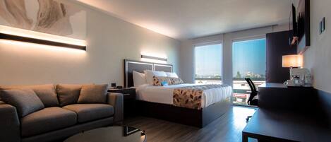 Una habitación de hotel moderna con cama, sofá y una pequeña mesa.