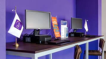 A workspace with two computers, a keyboard, a mouse, and a desk lamp.