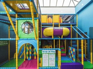 An indoor play area with a netted structure, a slide, and a circular climbing area. - Lovely 3-bed Caravan in Towyn (Abergele)
