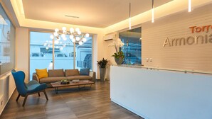 A modern reception area with a reception desk, a chandelier, a sofa, and a coffee table. - Getaway 1BR-WiFi-AC-View-Gym-BlueMall-YellowKey (Santo Domingo)