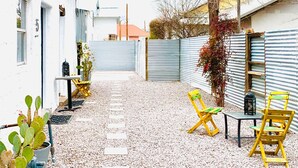 A courtyard with a gravel path, potted plants, and outdoor furniture.