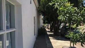 A narrow sidewalk adjacent to a white building with large windows.