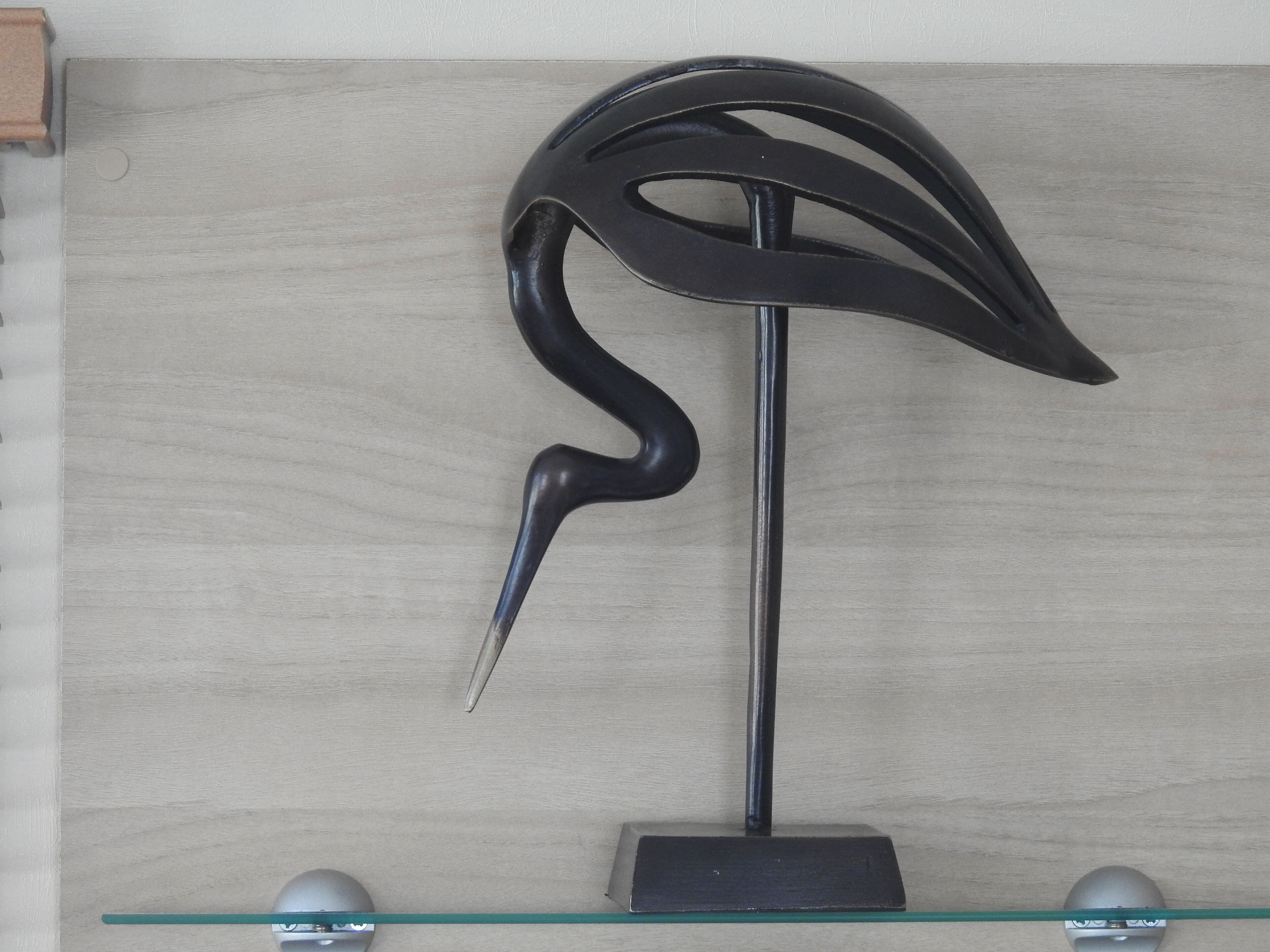 A sculpture on a glass shelf against a wooden wall.