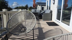 A patio with wicker furniture, a glass table, and a sliding glass door to a house.