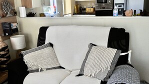 A living room with a sofa, two patterned throw pillows, a lamp, and a bookshelf.