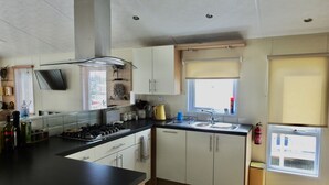 A modern kitchen with a black countertop, white cabinets, a gas stove, and a window with blinds.