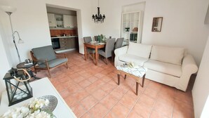A living room with a sofa, chairs, a dining table, and a kitchen in the background. - Qanat House_apartment with terrace- In the countryside in the heart of the city (Palermo)