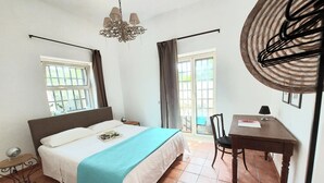 A bedroom with a bed, a desk, a chair, a chandelier, and a window with curtains. - Qanat House_apartment with terrace- In the countryside in the heart of the city (Palermo)
