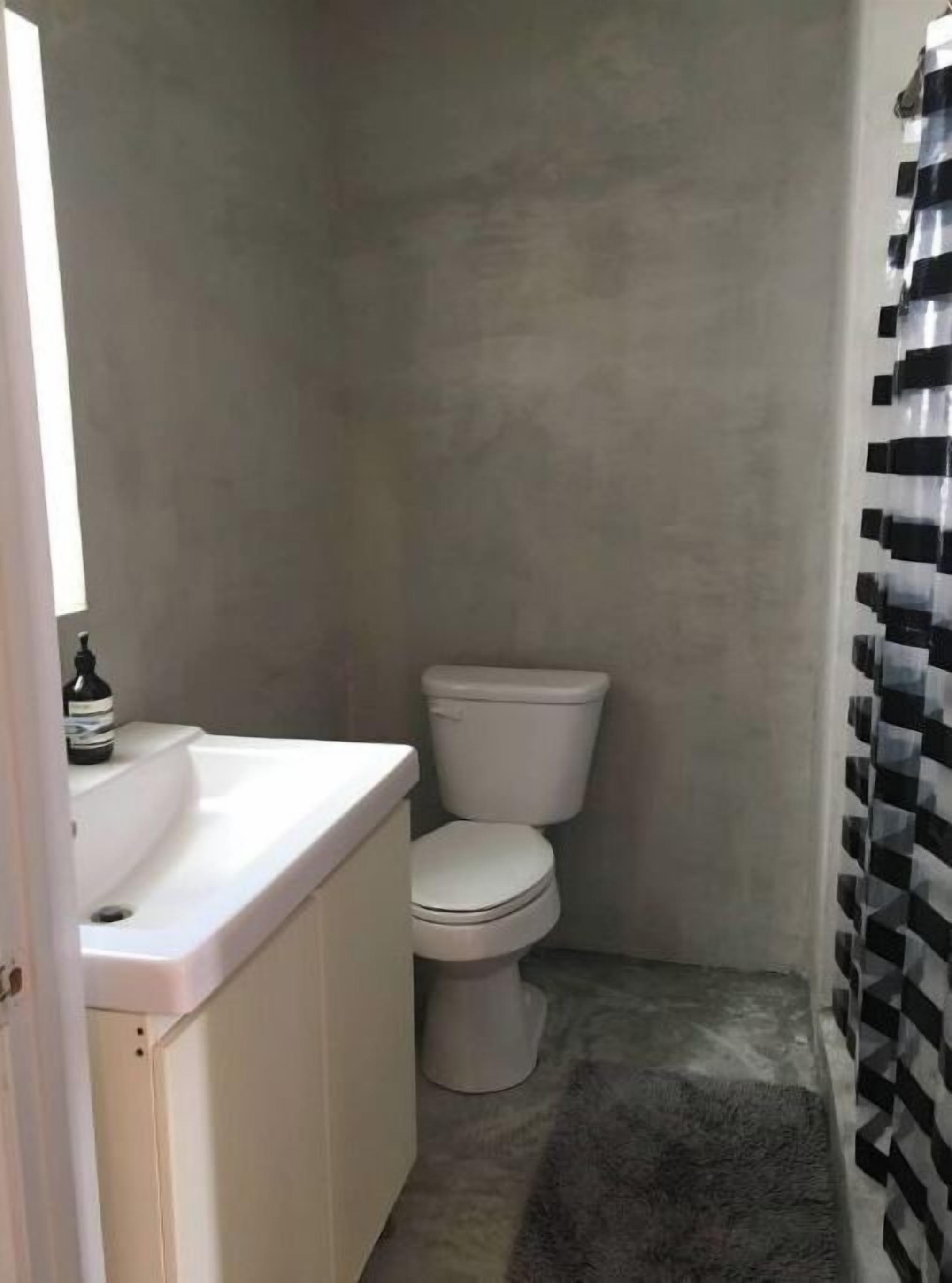 A small, narrow bathroom with a white sink and toilet.