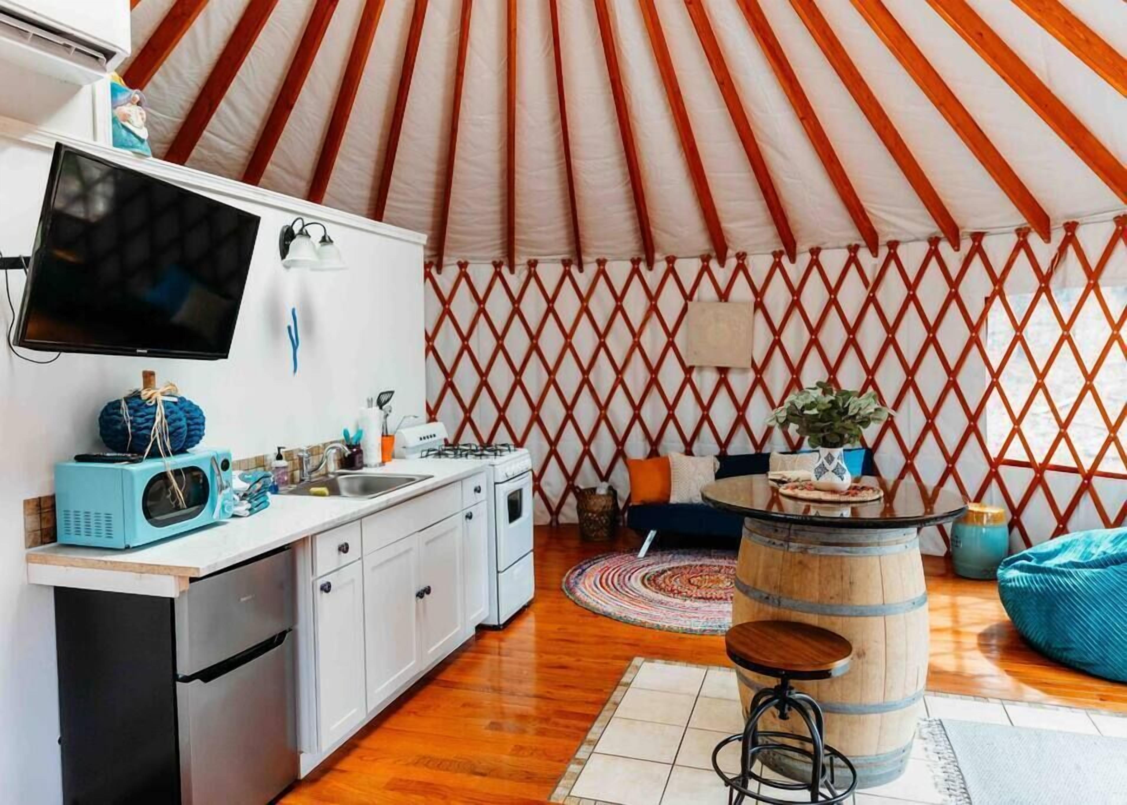 Una cucina moderna con un grande televisore, un forno a microonde e un piano cottura. C'è un'area pranzo con un tavolo rotondo e sedie.