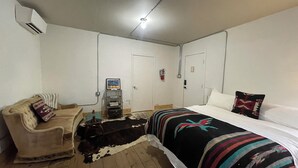 Un dormitorio con una cama, un sofá, un calentador, un aire acondicionado instalado en la pared y una puerta.
