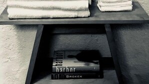 Una pila de toallas blancas sobre una estantería y un libro con el título 'harbor' y la palabra 'BROKEN' en la portada.