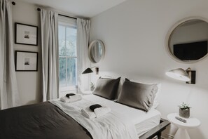 Een keurig opgemaakte slaapkamer met een bed, nachtkastje, lamp en een kleine potplant.