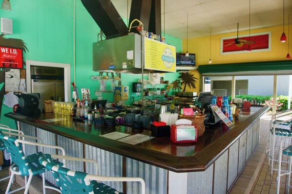 A bar area with a counter, bar stools, and various items like bottles and a menu.