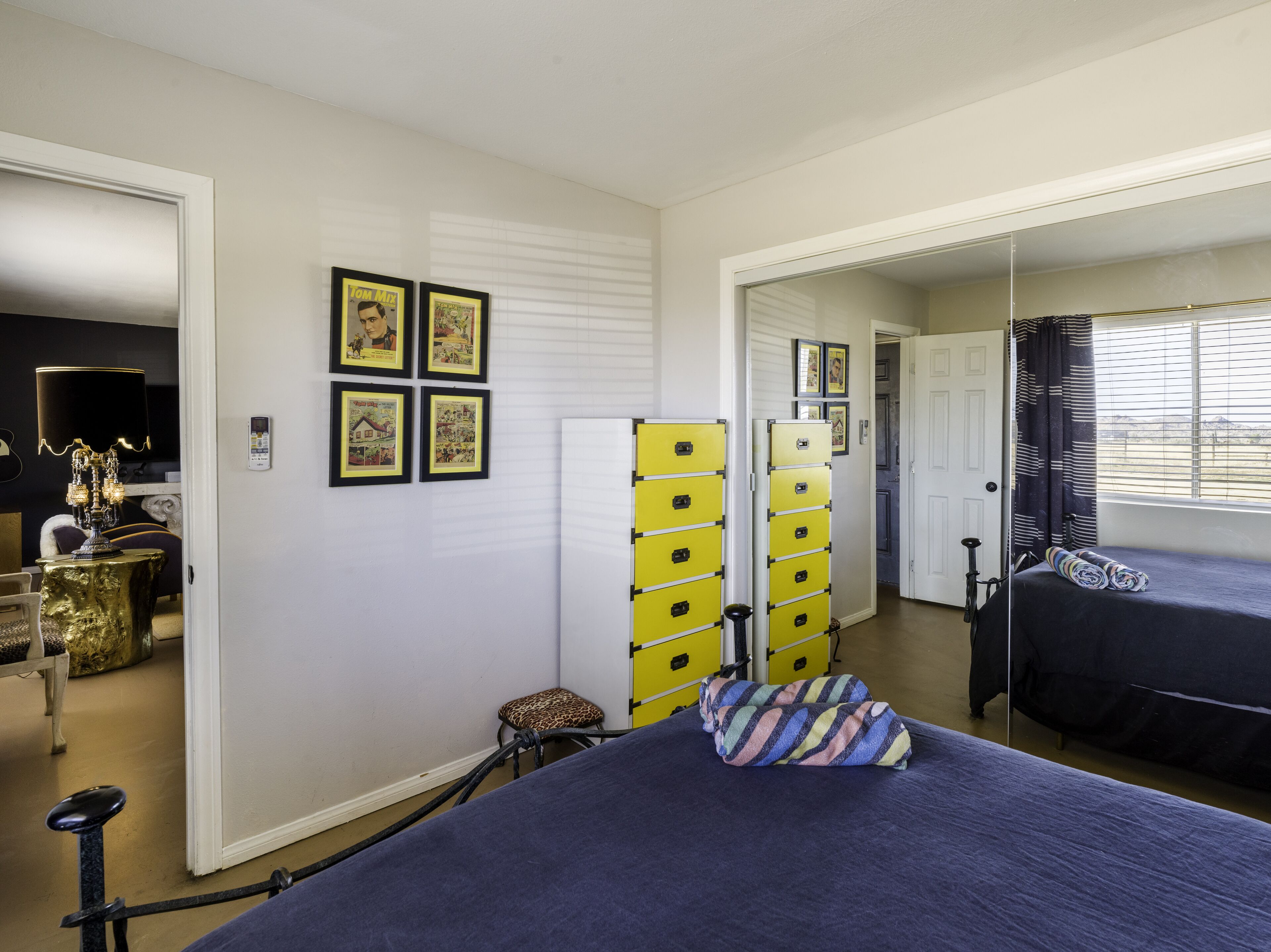 A bedroom with a bed, a mirror, a dresser, and a lamp.