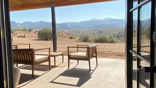 A room with a sliding glass door leading to an outdoor patio with a view of mountains. - Chasing The Moon: Walk to Pappy's & Tub Views (Pioneertown)