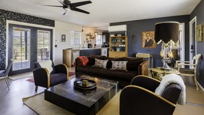 A modern living room with a dark brown sofa, a black coffee table, and a ceiling fan. - Chasing The Moon: Walk to Pappy's & Tub Views (Pioneertown)