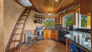 Une cuisine avec des meubles de rangement en bois, une cuisinière, un four à micro-ondes et une grande fenêtre.