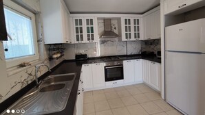 Una cocina con armarios blancos, encimera negra, un lavabo, una estufa y un refrigerador.