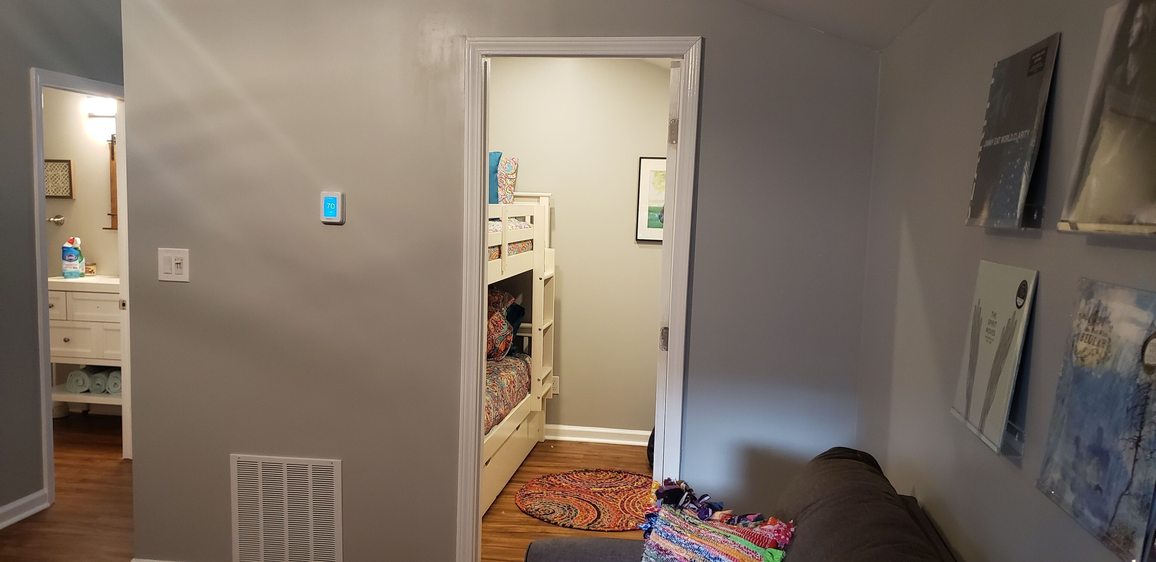 A hallway with a bunk bed, a white dresser, and a door leading to another room.