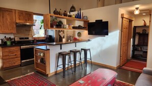 A modern kitchen with wooden cabinets, a built-in stove, and a bar area with stools. - Clean, one bedroom, newly constructed home within walking distance of downtown.  (Bozeman)