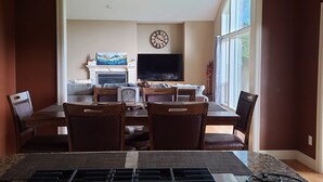 Un comedor con chimenea, televisión y un ventanal grande.