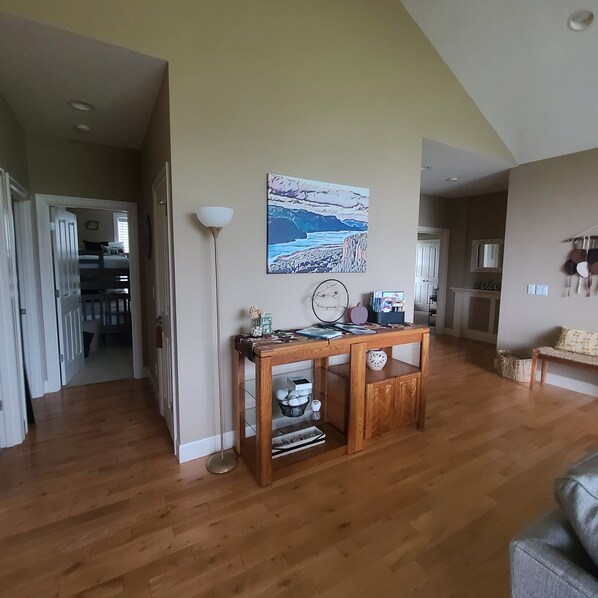 Ein geräumiges Wohnzimmer mit Holzboden, einem Essbereich mit Tisch und Stühlen sowie einer Küche im Hintergrund.