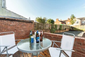 An outdoor patio with a round glass table and two white chairs. - WGcDDE Large 3 Bedroom House - Parking - Garden (Kingston upon Hull)