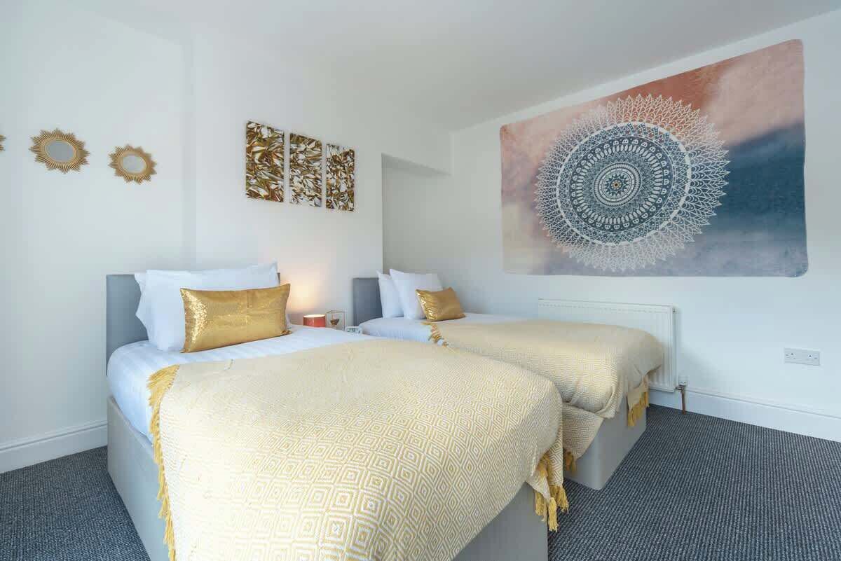 Une chambre d’hôtel avec deux lits, une grande tapisserie murale et des œuvres d’art décoratives accrochées au mur.