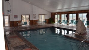 En indendørs swimmingpool med liggestole og et overdækket opholdsområde.