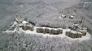 Et sneklædt resort med flere bygninger, en skibakke og et skovområde.