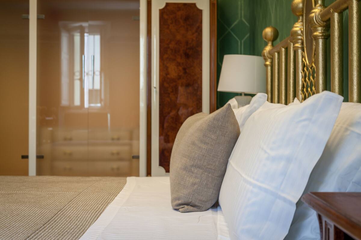 Una habitación de hotel con una cama, cabecera de madera, mesita de noche y una lámpara.
