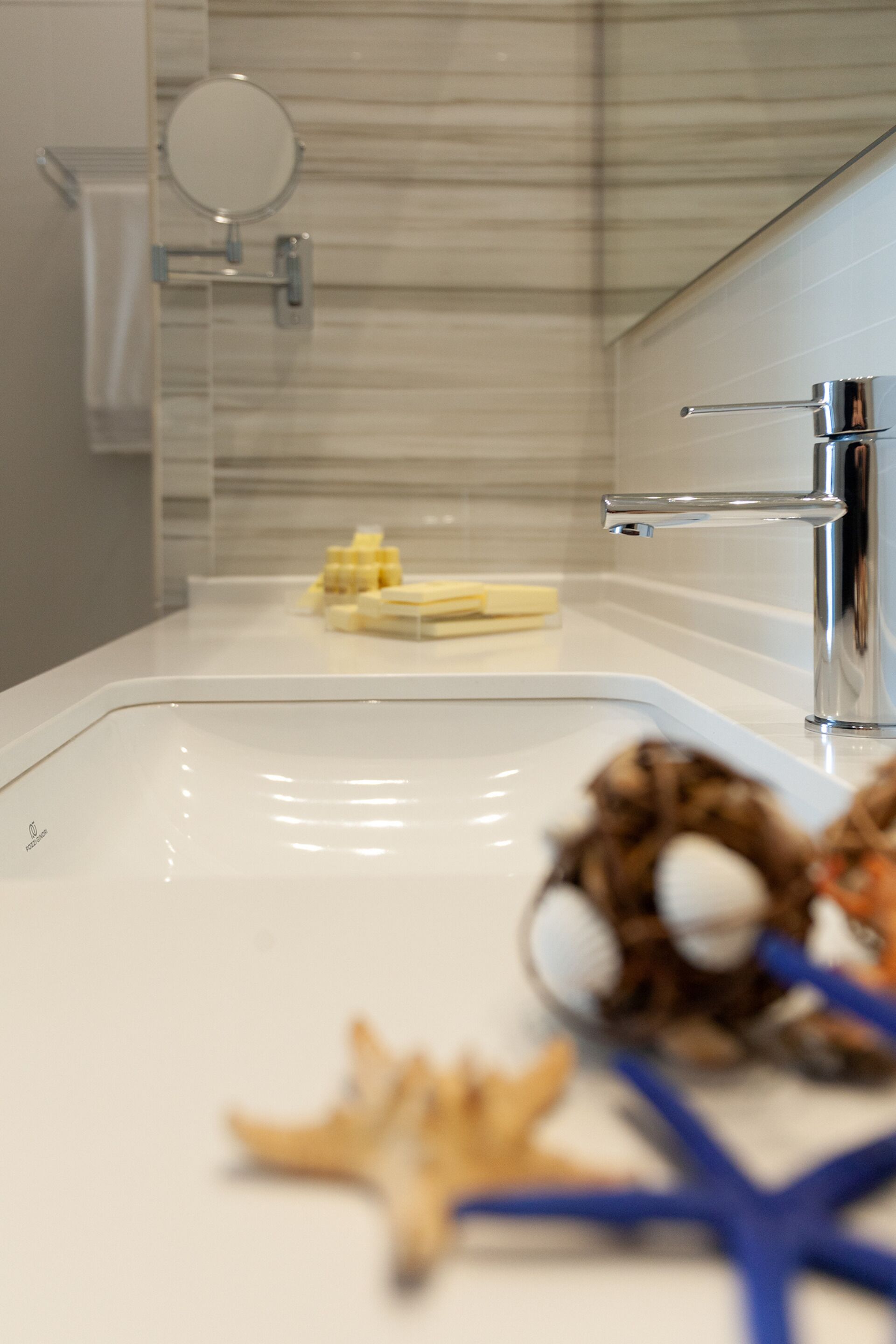 Un baño con lavamanos blanco, un espejo y artículos de tocador en la encimera.