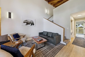 A modern living room with a sofa, a coffee table, and a bear artwork on the wall. - Tahoe Mountain Condo with Tree Filtered Lake Views. (Stateline)
