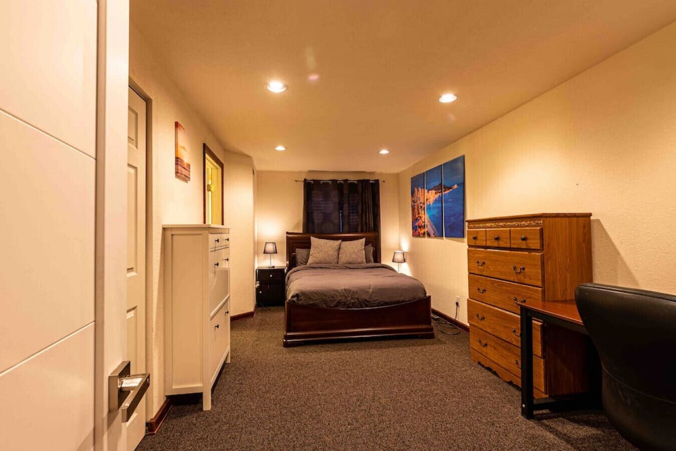 A bedroom with a bed, dresser, nightstands, and a desk.