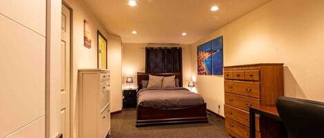 A bedroom with a bed, dresser, nightstands, and a desk.