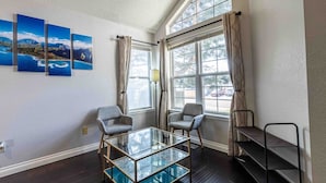 A room with a glass-top table, two chairs, a bookshelf, and a window with curtains. - Hot Tub | Theater | Firepit | Gym | Yard | Foosbal (Colorado Springs)