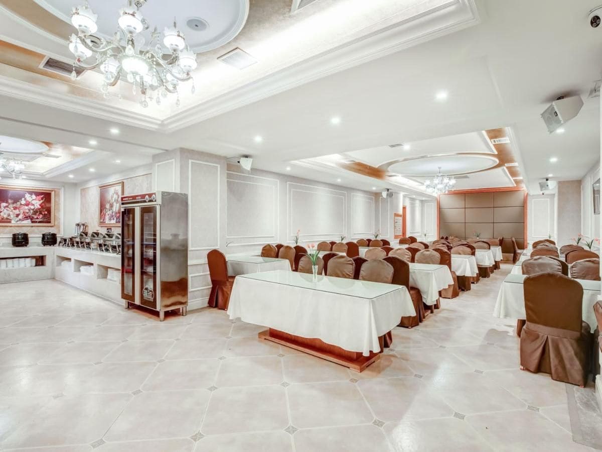A banquet hall with multiple tables, chairs, and a buffet area.